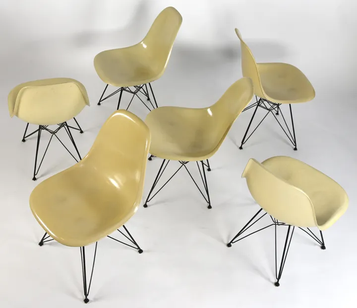 Six stolen Eames chairs with cream-colored shells and black wire bases.