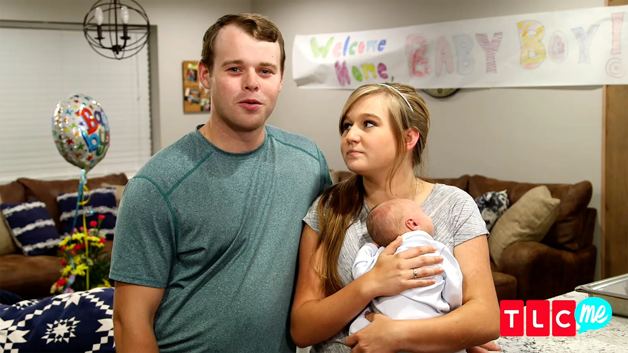 Joseph and Kendra Duggar standing with their baby and a 