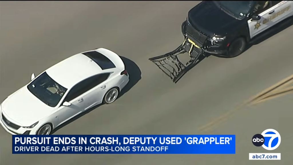 A white car next to a police car with a grappler device deployed.
