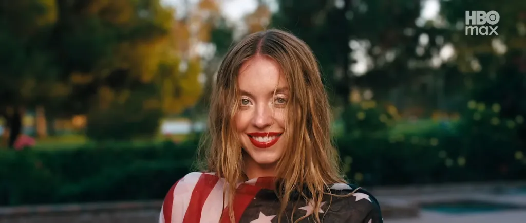 A woman with blonde hair, red lipstick, and a red, white, and blue top smiling at the camera.