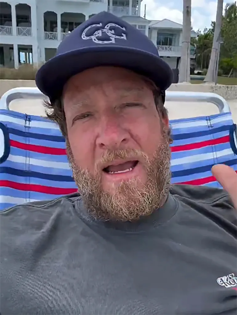 Dave Portnoy sitting in a beach chair with a large white house and palm trees in the background.