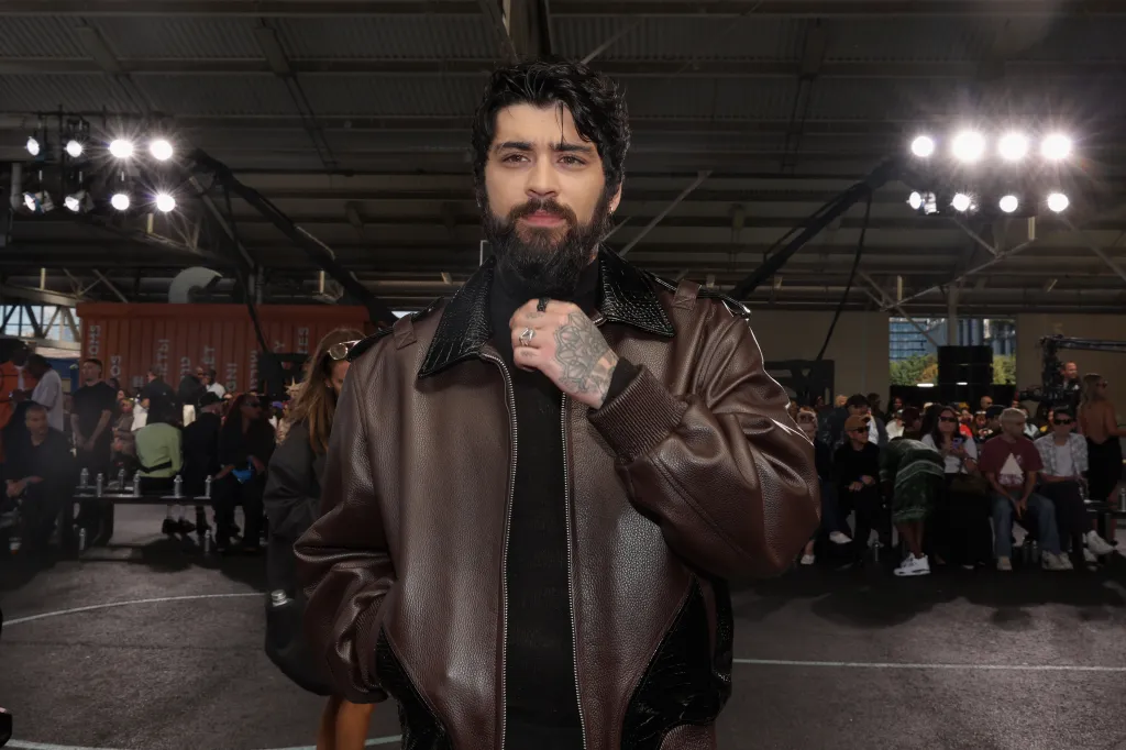 Zayn Malik in a brown leather jacket and black turtleneck attends the Off-White fashion show.