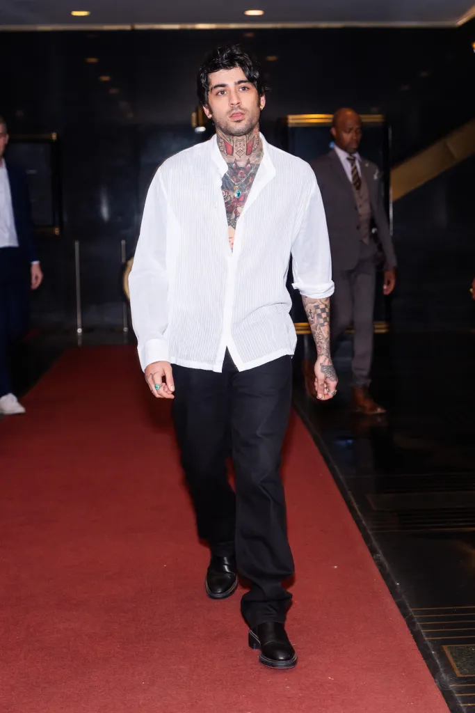 Zayn Malik walking on a red carpet.