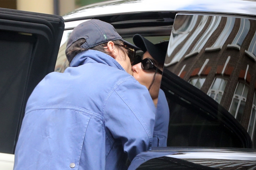 Harry Styles and Zoë Kravitz share a public kiss, both wearing baseball caps and sunglasses.