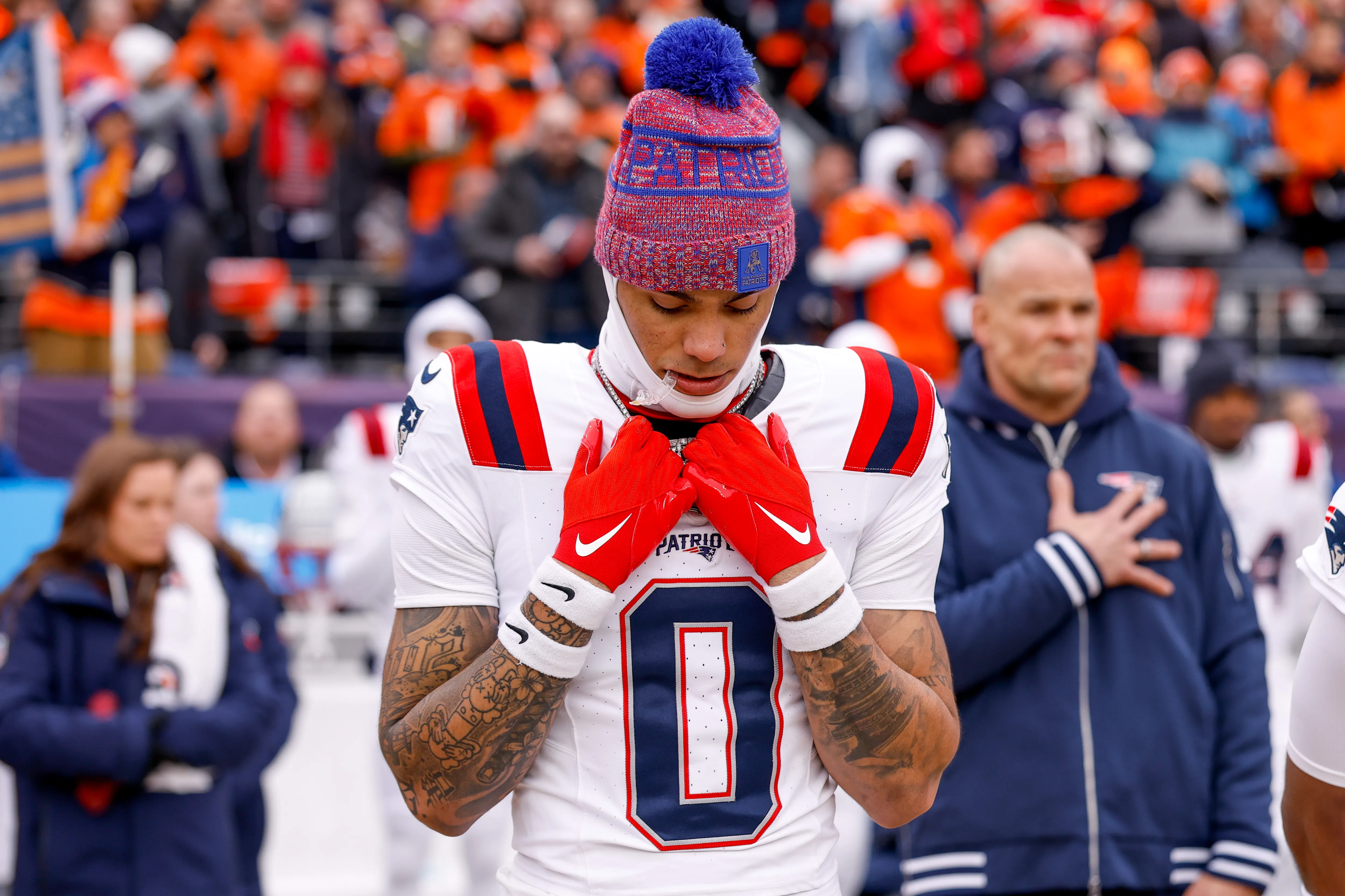 Christian Gonzalez of the New England Patriots stands for the national anthem with his hands over his heart.