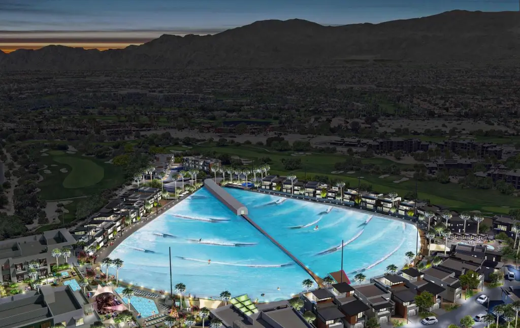 Illustration of a luxurious surf park with a large wave pool surrounded by homes and palm trees, set against a mountain range at dusk.