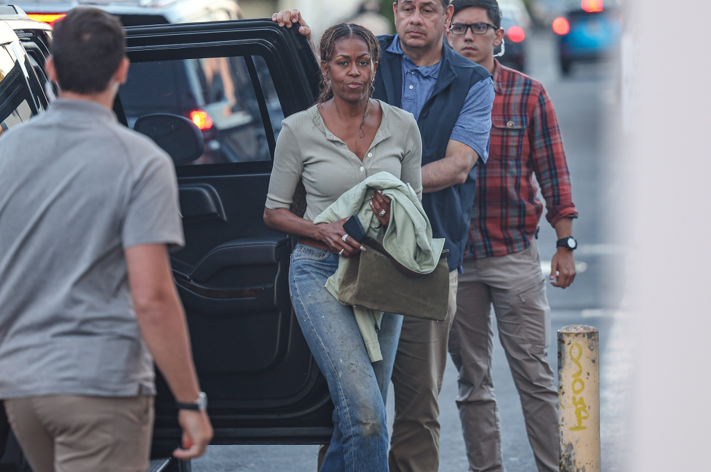 Michelle Obama exiting a vehicle with two men.