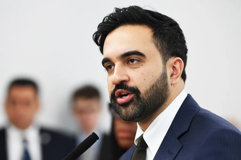 NYC Council Member Zohran Mamdani speaking at a microphone.