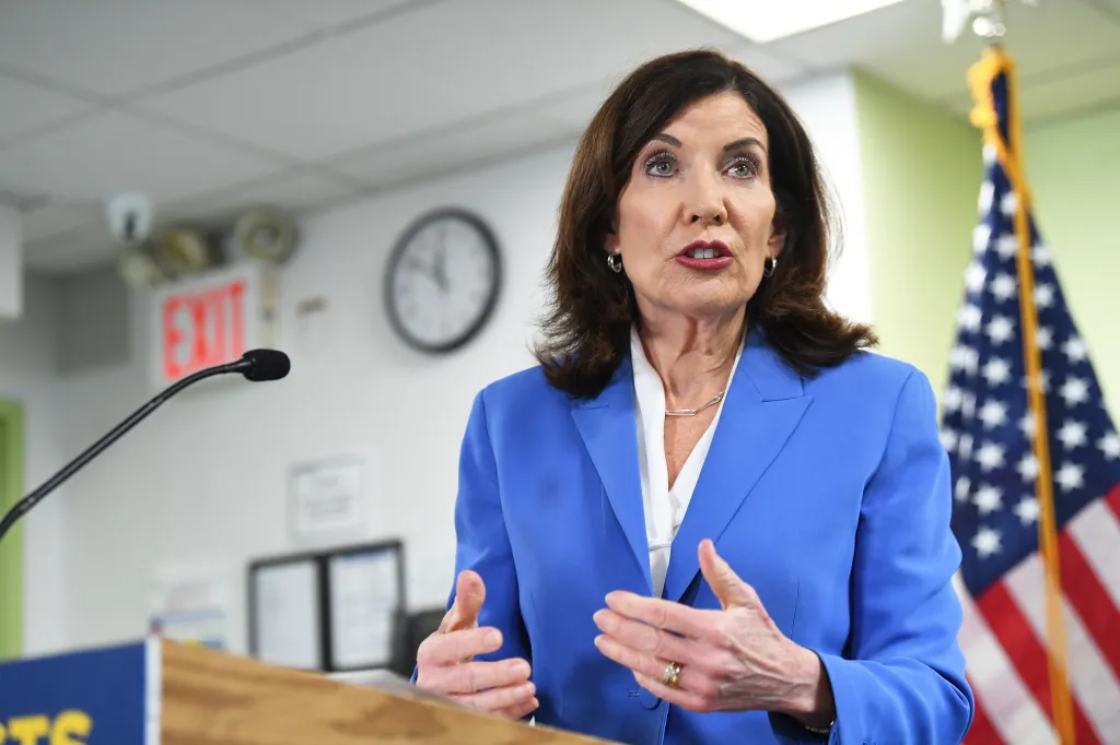Governor Kathy Hochul speaking at a podium with an American flag in the background.