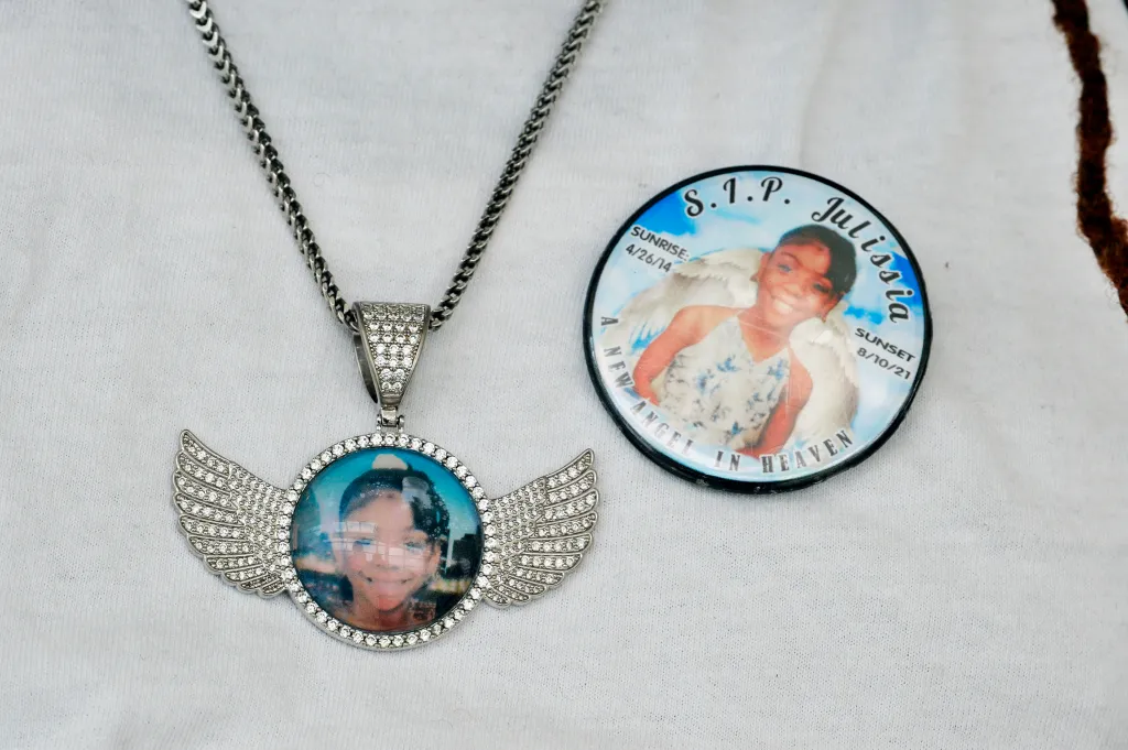 A necklace with a winged pendant showing a photo of Julissia Batties and a button with the text 