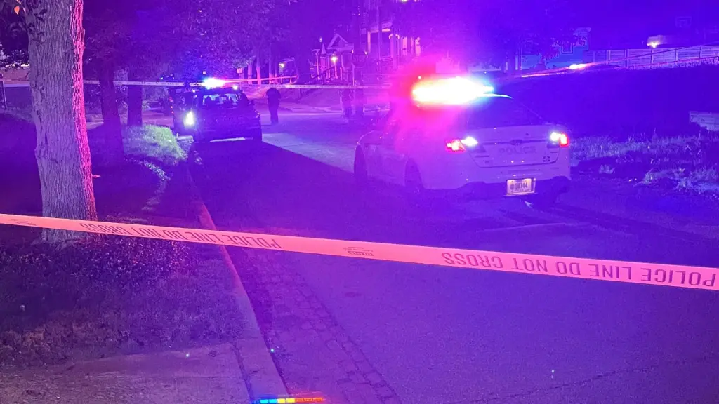 Police cars with flashing lights at night behind yellow 