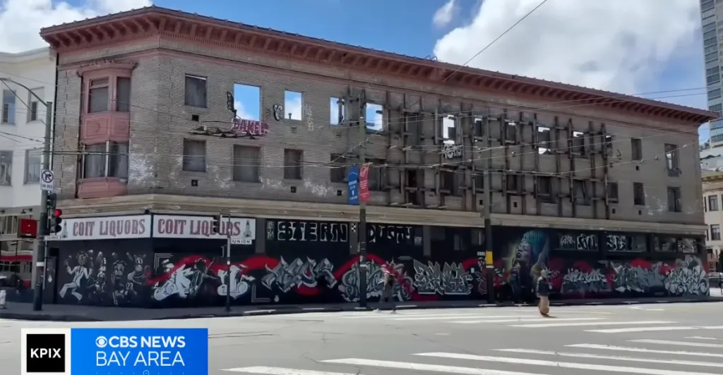 The Verdi building in ruins, with its windows removed and a large mural covering the first floor.
