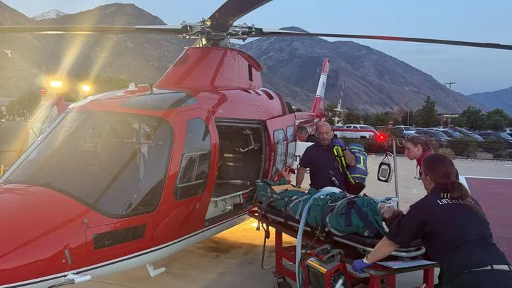 Medical personnel unload a patient from a red helicopter on a gurney.