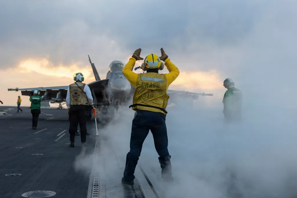 A U.S. sailor signals an F/A-18F Super Hornet aircraft on the flight deck of the USS George H. W. Bush.
