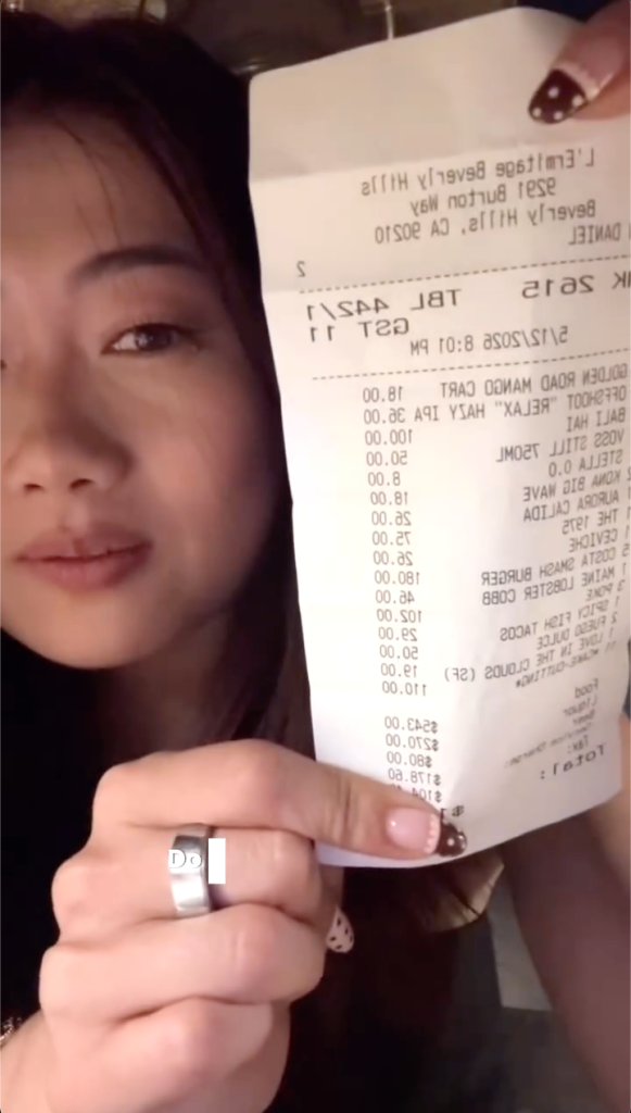 A woman holds up a restaurant receipt showing various charges, including an $11 charge for 