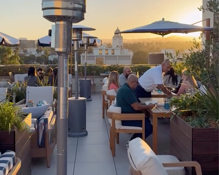People dining on a rooftop patio at sunset.