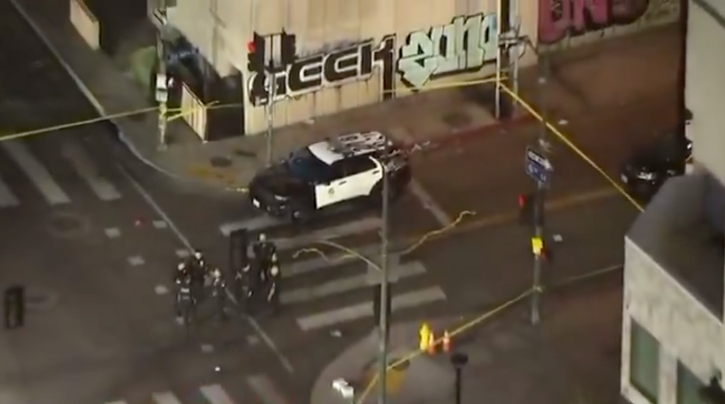 Overhead shot of a crime scene with a police car and officers on a city street.