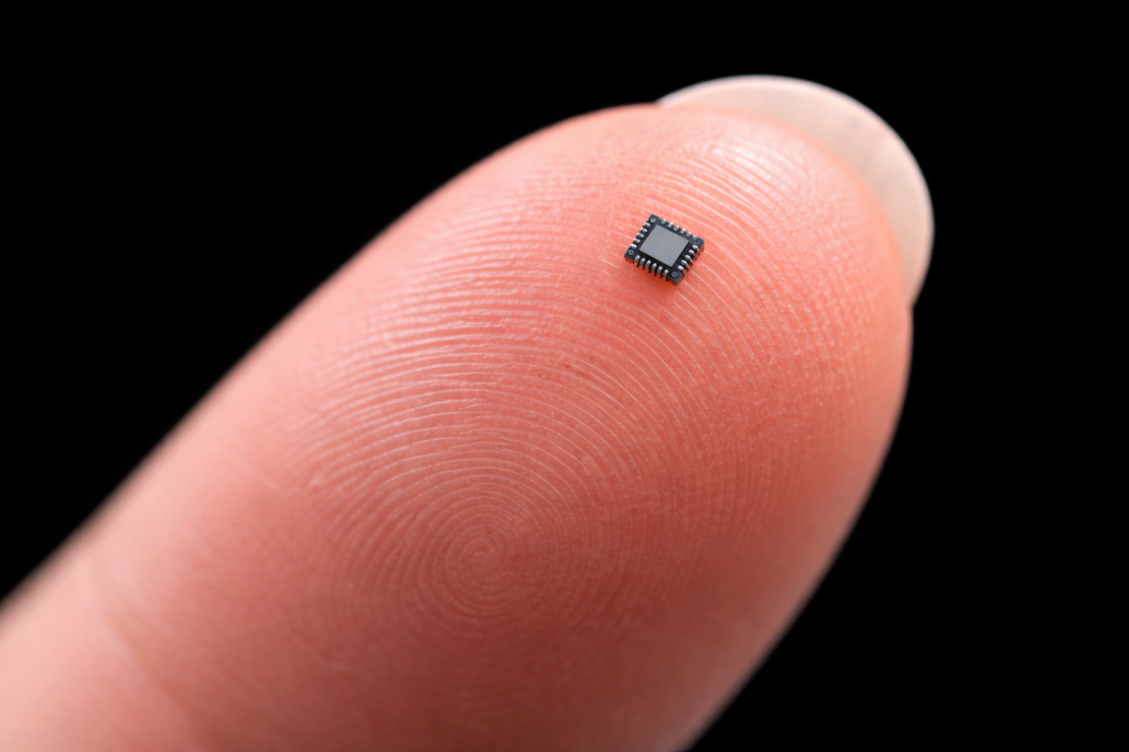 A small microchip rests on the tip of a finger.