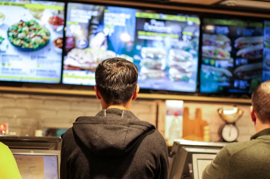 Man choosing a hamburger from the menu of a fast food restaurant.