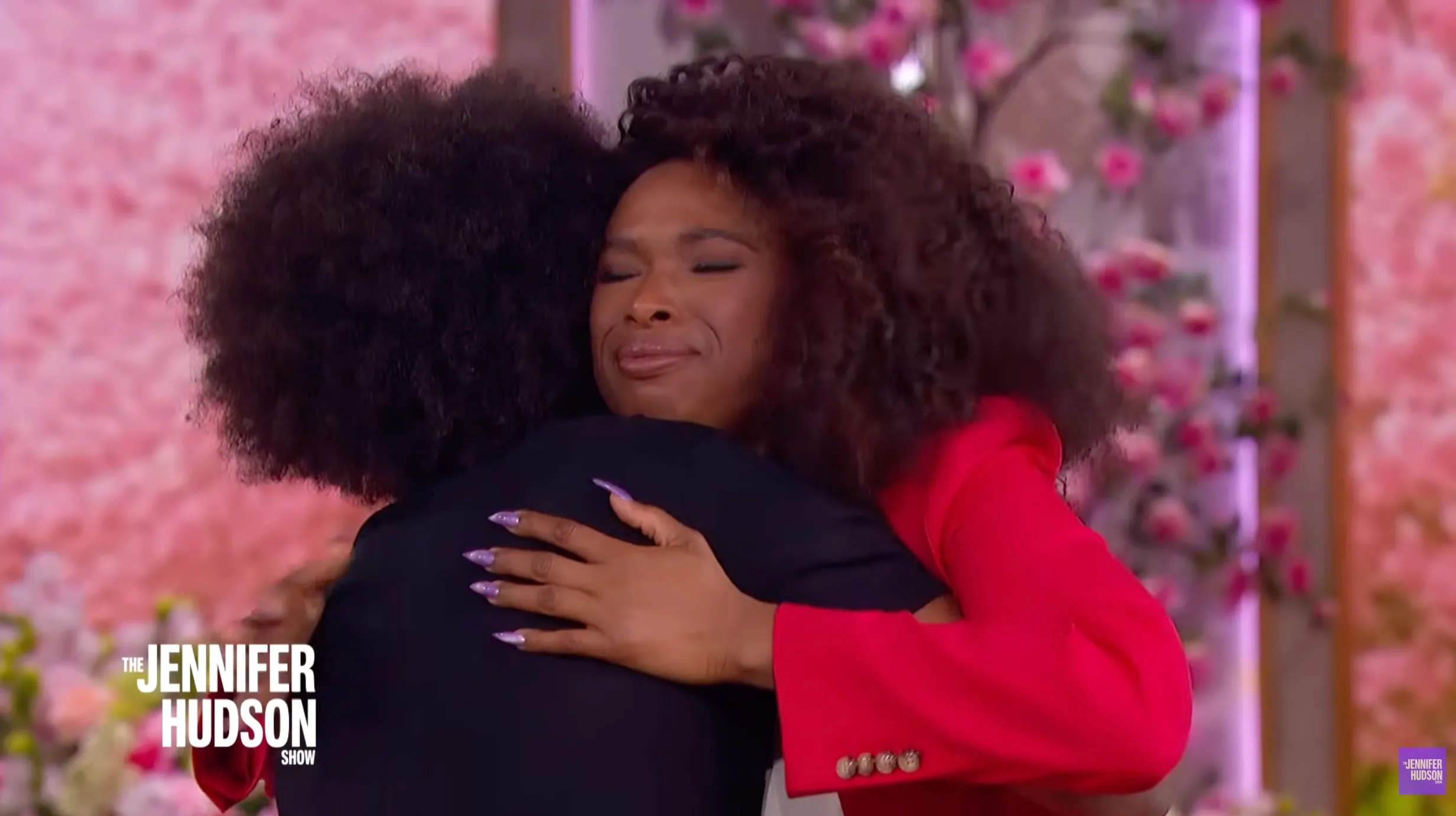 Jennifer Hudson in a red blazer hugging a guest with afro-textured hair on 