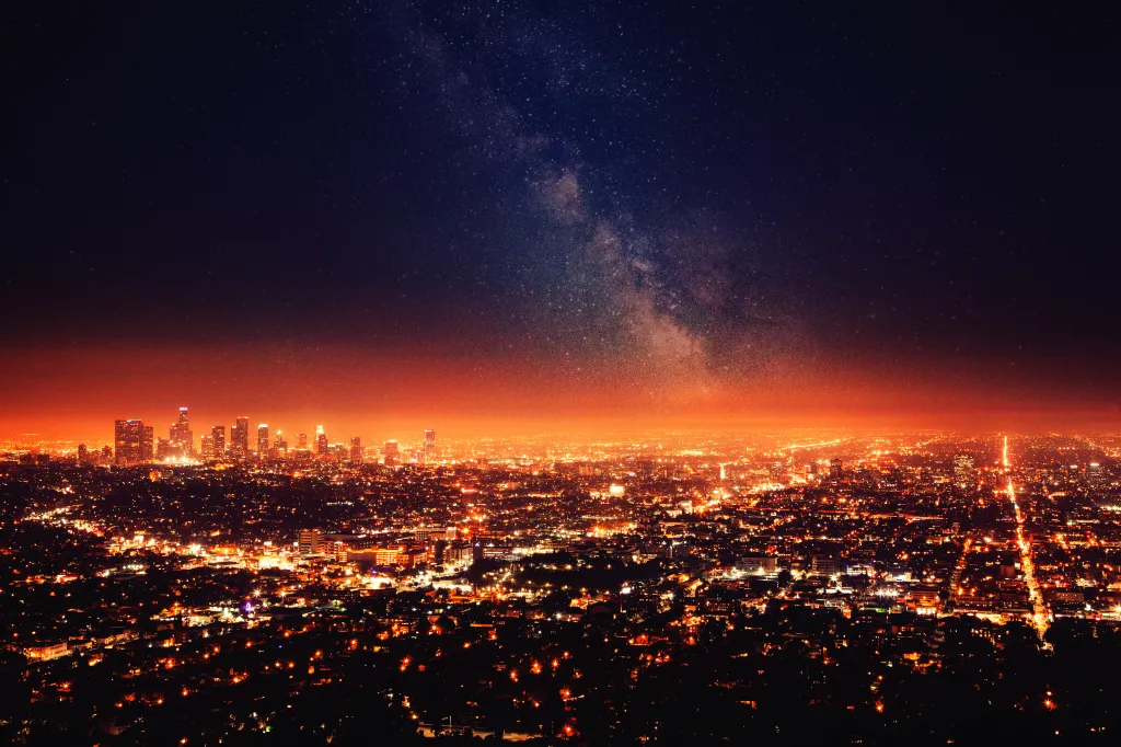 The Milky Way galaxy visible above the glowing city lights of Los Angeles at night.
