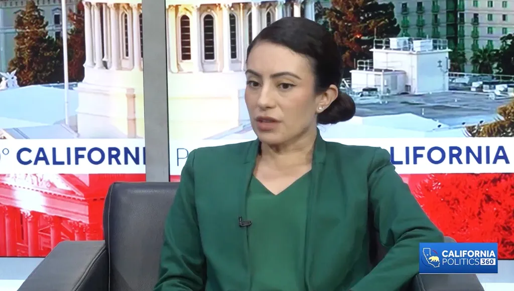 A woman in a green jacket speaking on 