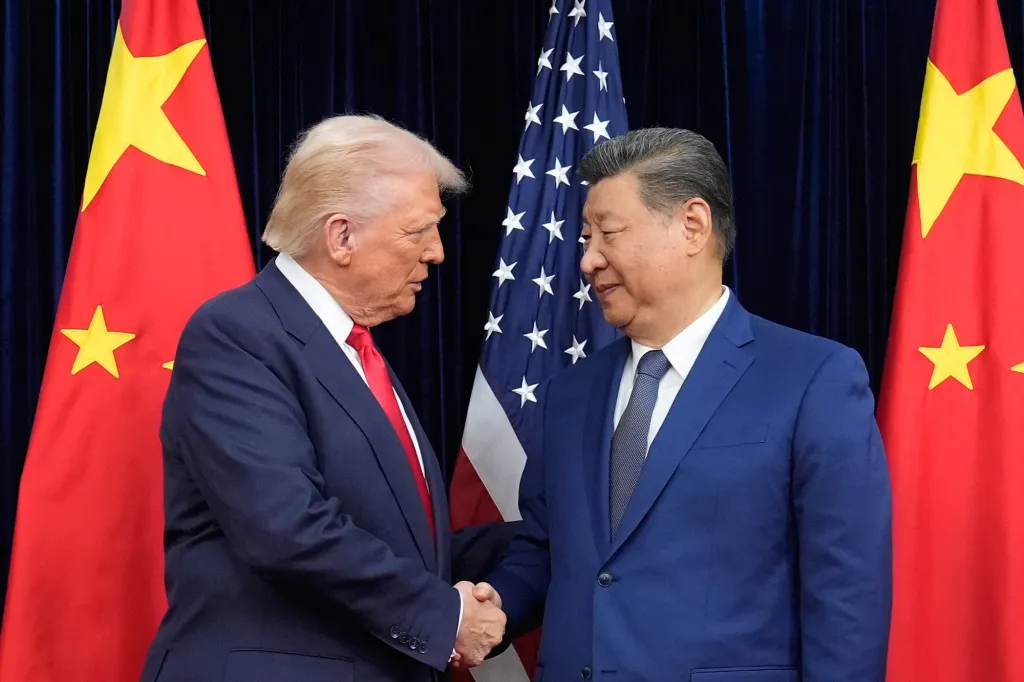 Donald Trump and Xi Jinping shaking hands in front of US and Chinese flags.