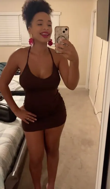 A woman in a brown dress taking a mirror selfie.