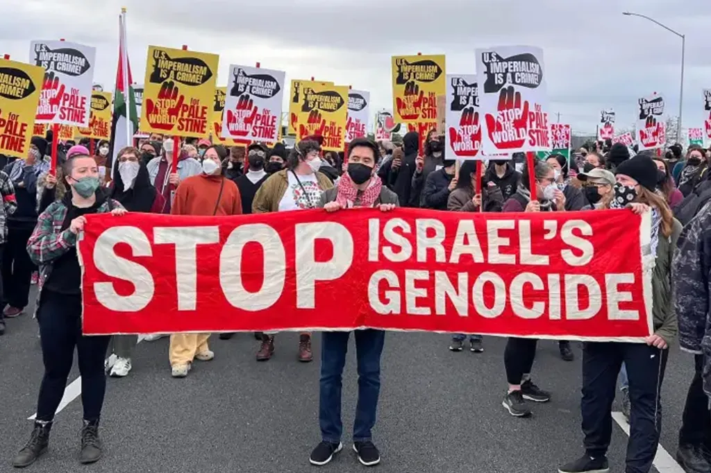 A group of protestors holding signs, the largest reads 