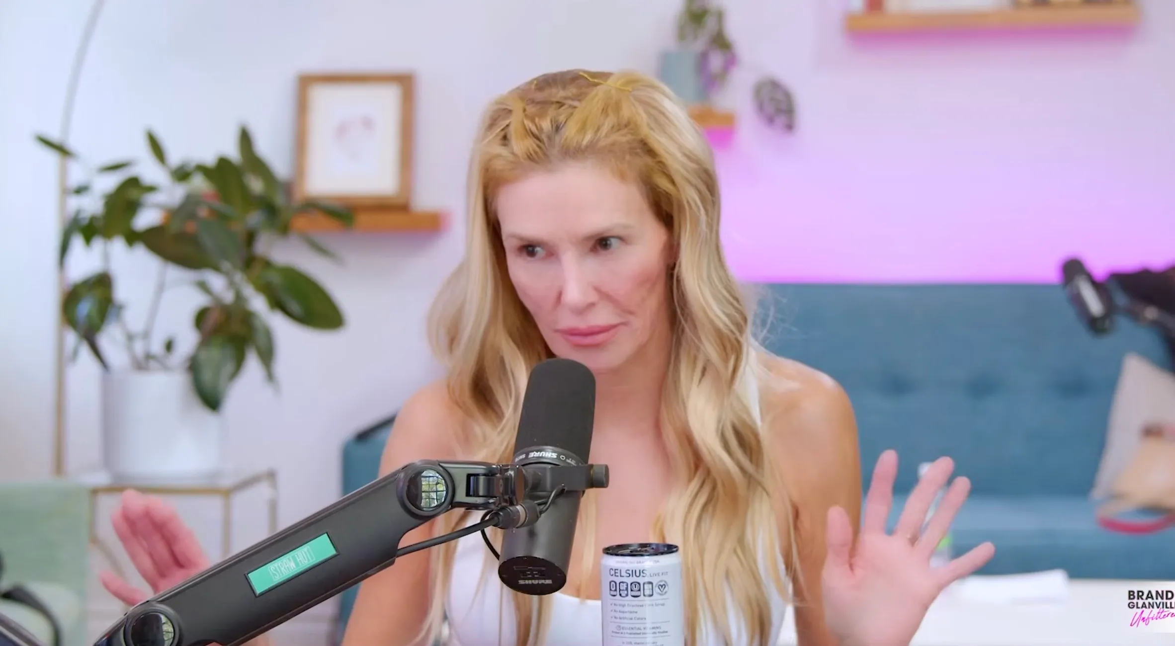Brandi Glanville with a microphone and a can of Celsius drink, discussing her 