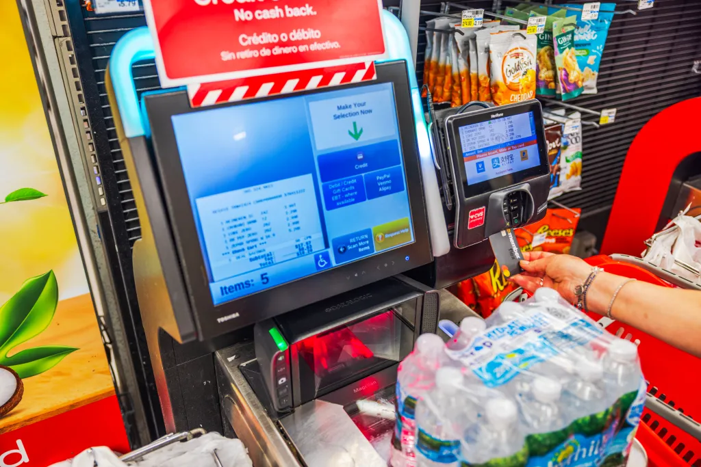 Woman paying for Zephyrhills water with a credit card at a CVS self-checkout.