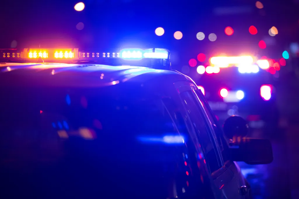 Police car with flashing blue and amber lights at night.