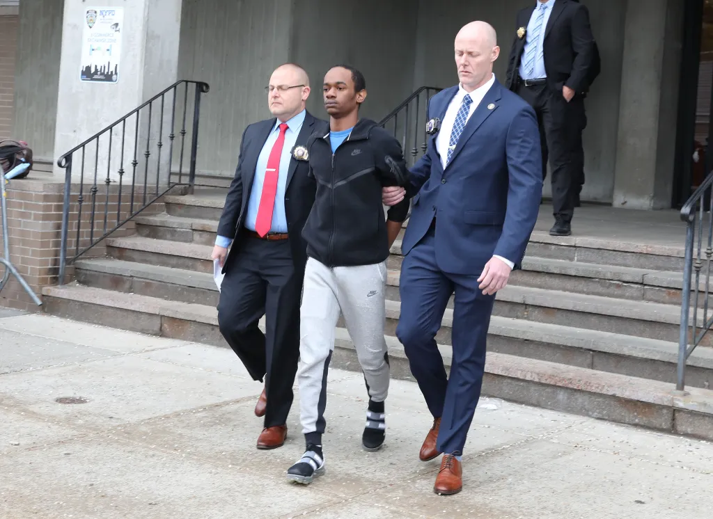 Zahir Davis, 18, being walked out of the 103rd Police Precinct in Queens, NY, flanked by two officers.