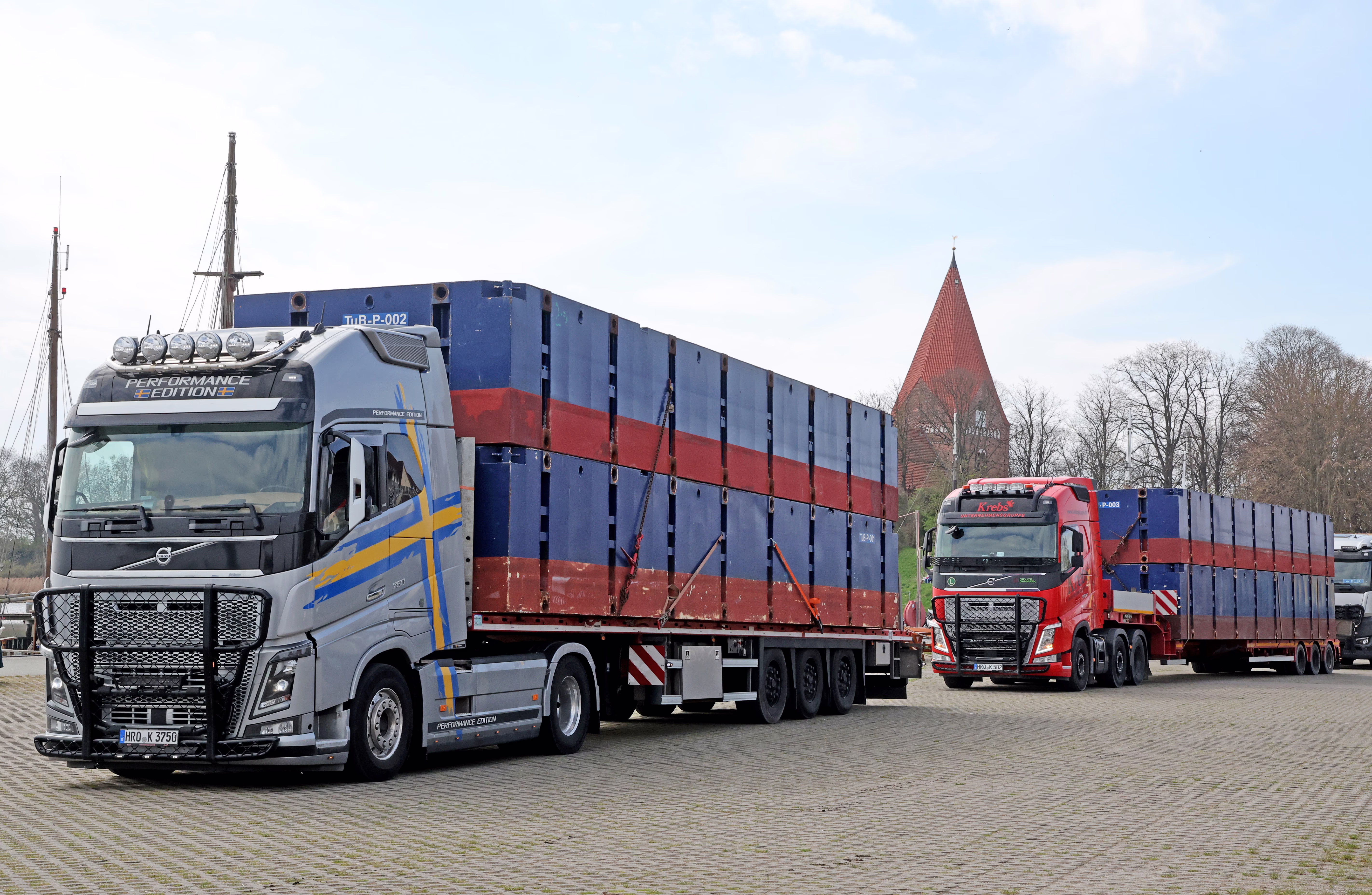 Trucks carry large pontoons to a port.