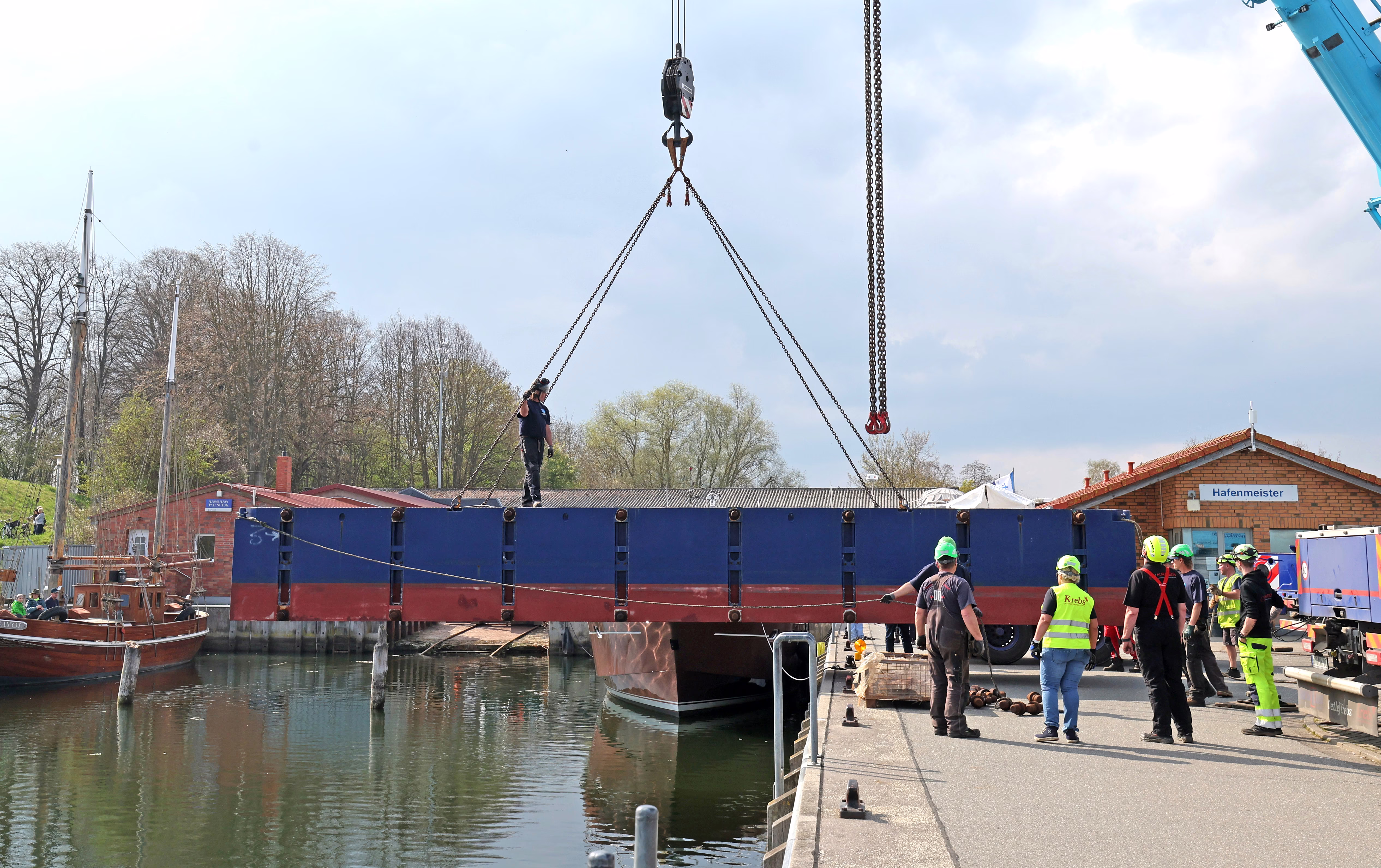 Pontoons are lowered into a port with a crane.
