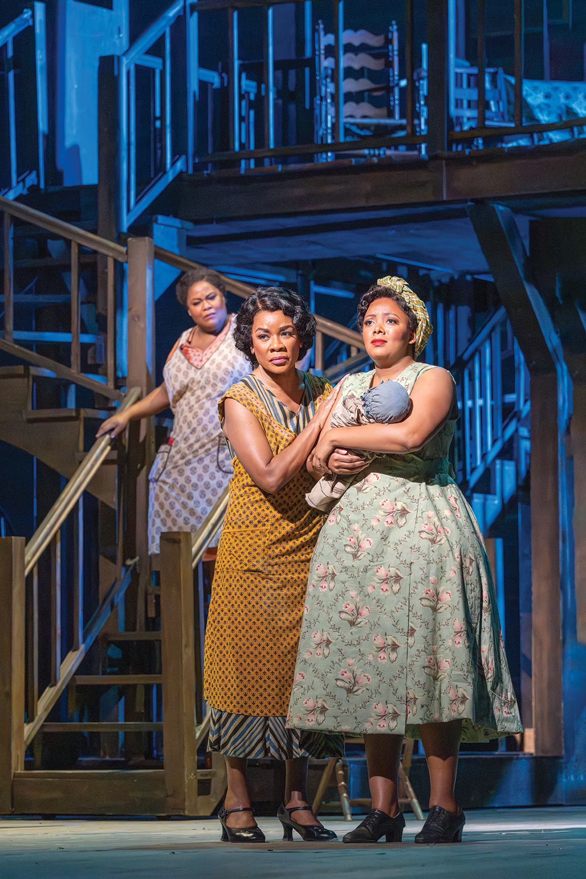 photo of 3 women on stage, one holding baby