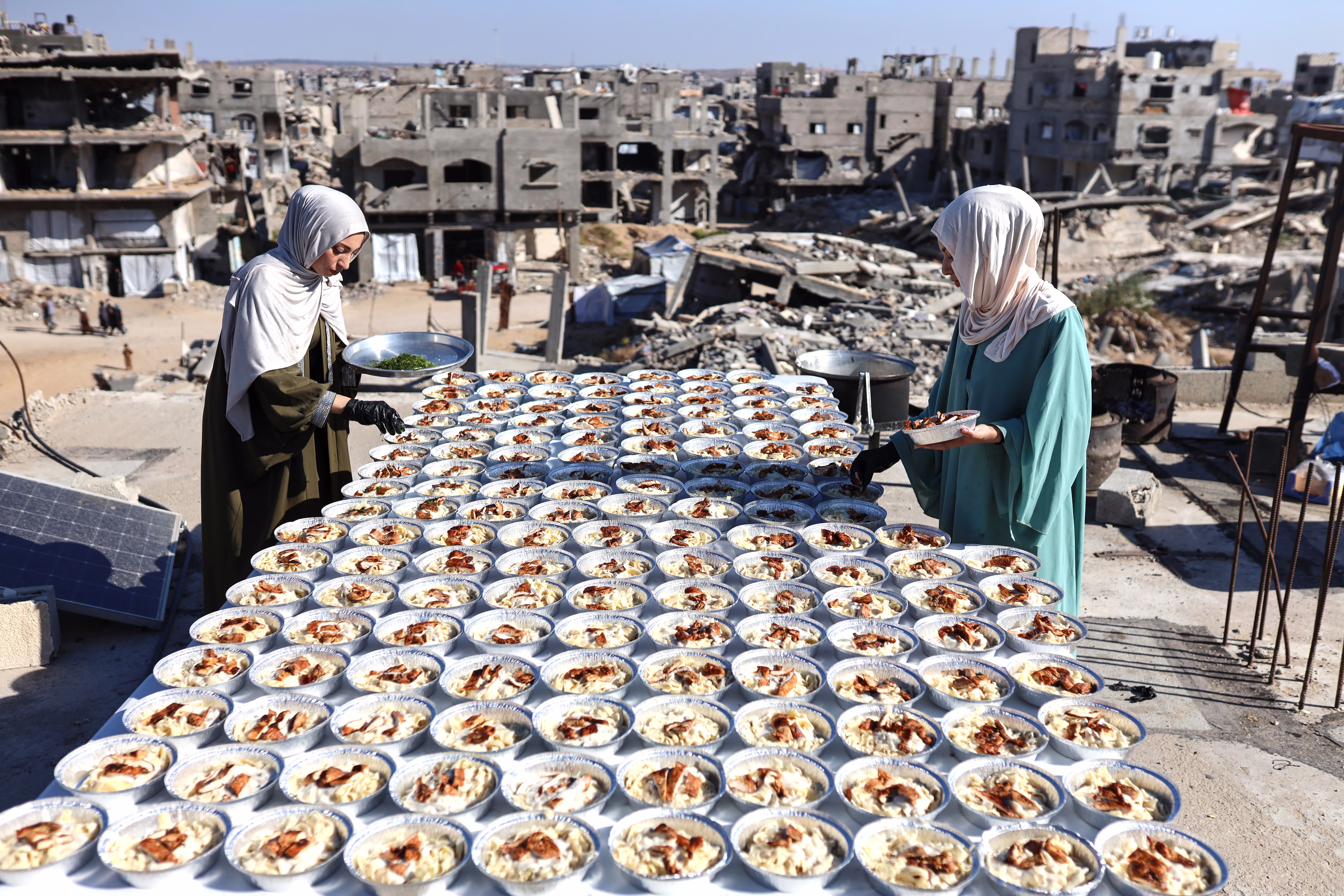 Two sisters prepare dozens of food plates on the rooftop of their house in Gaza.