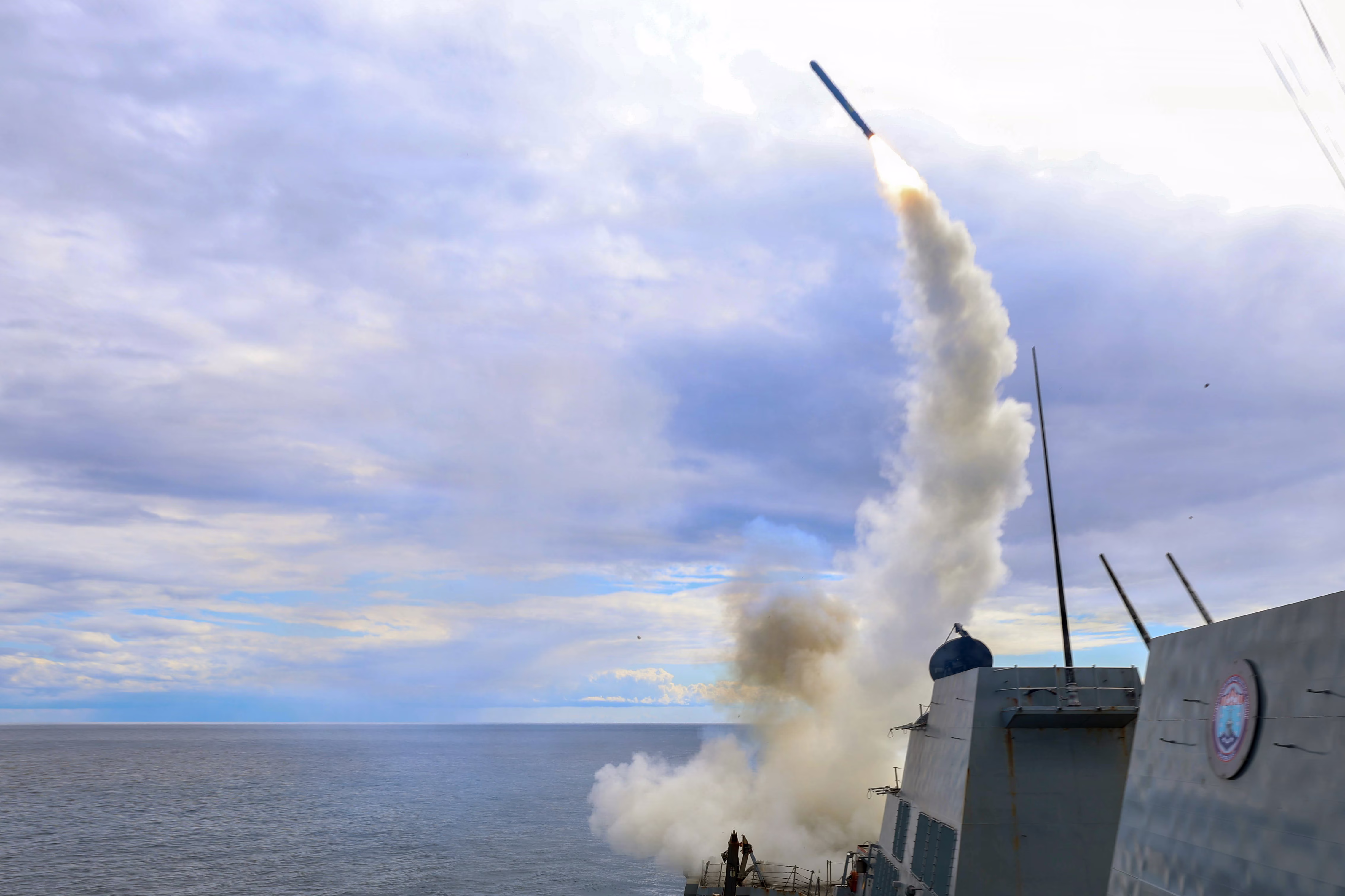 A missile launches from the deck of a ship.