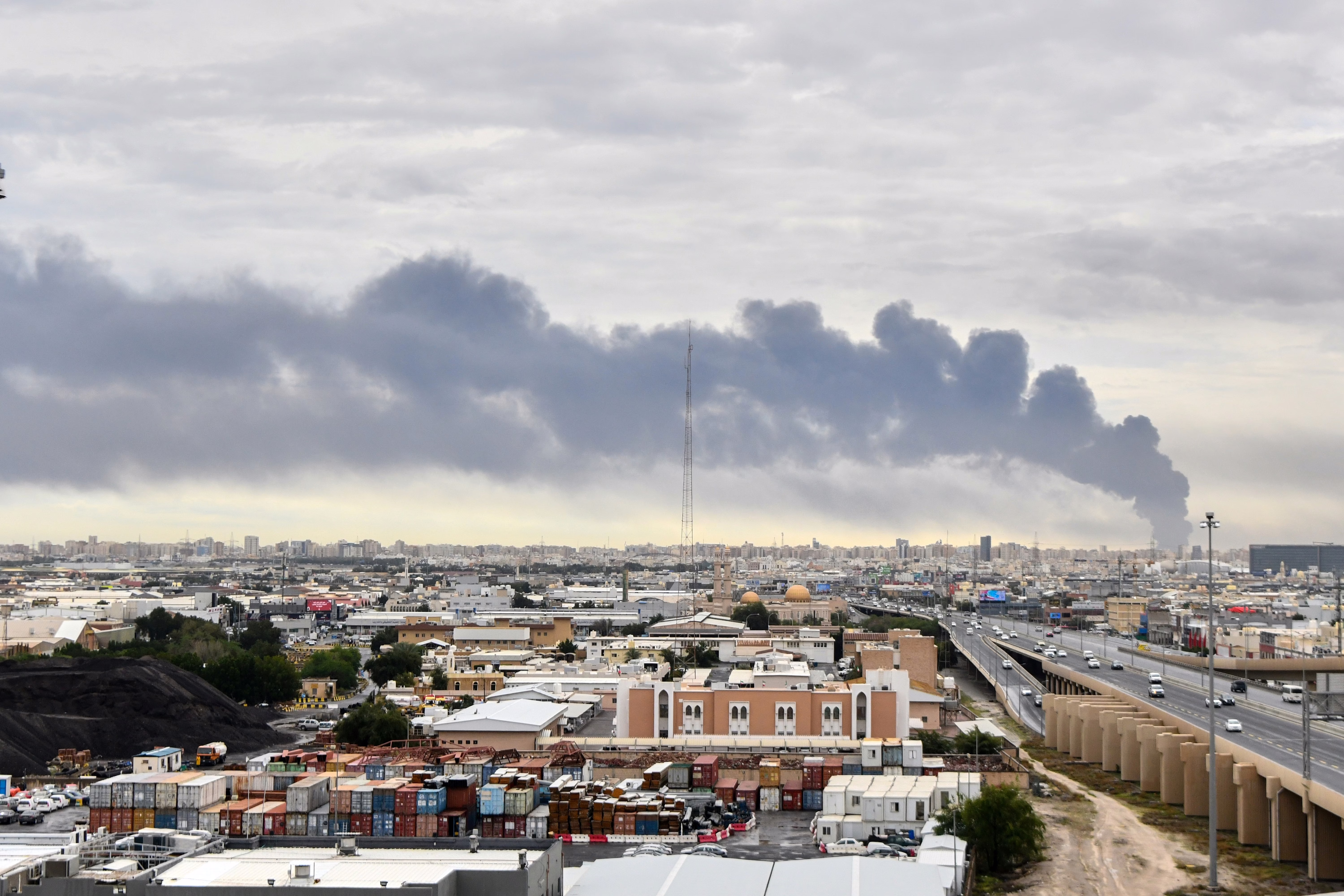 Dark smoke rises above buildings, seen from a distance.