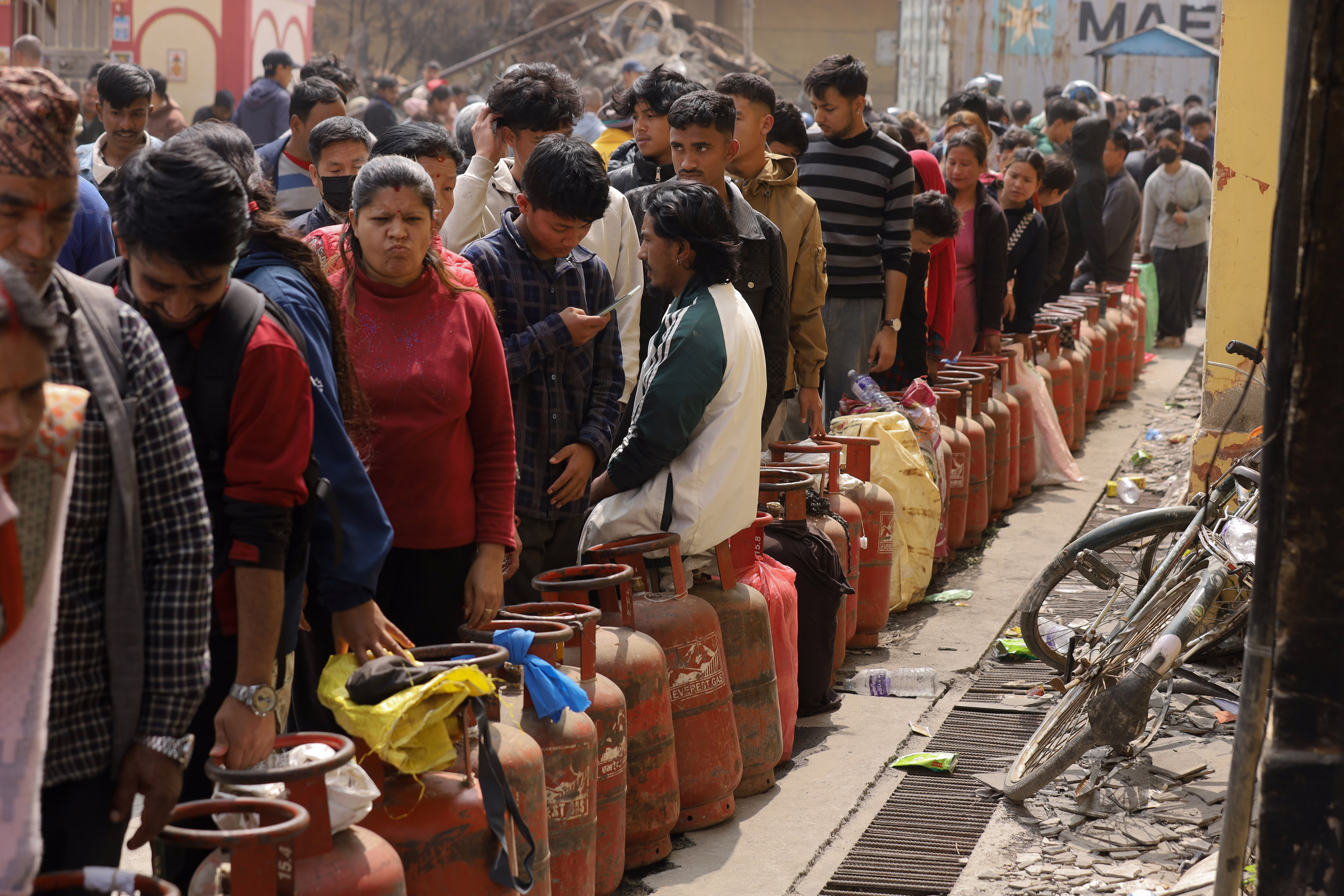 People wait in long line with gas canisters.