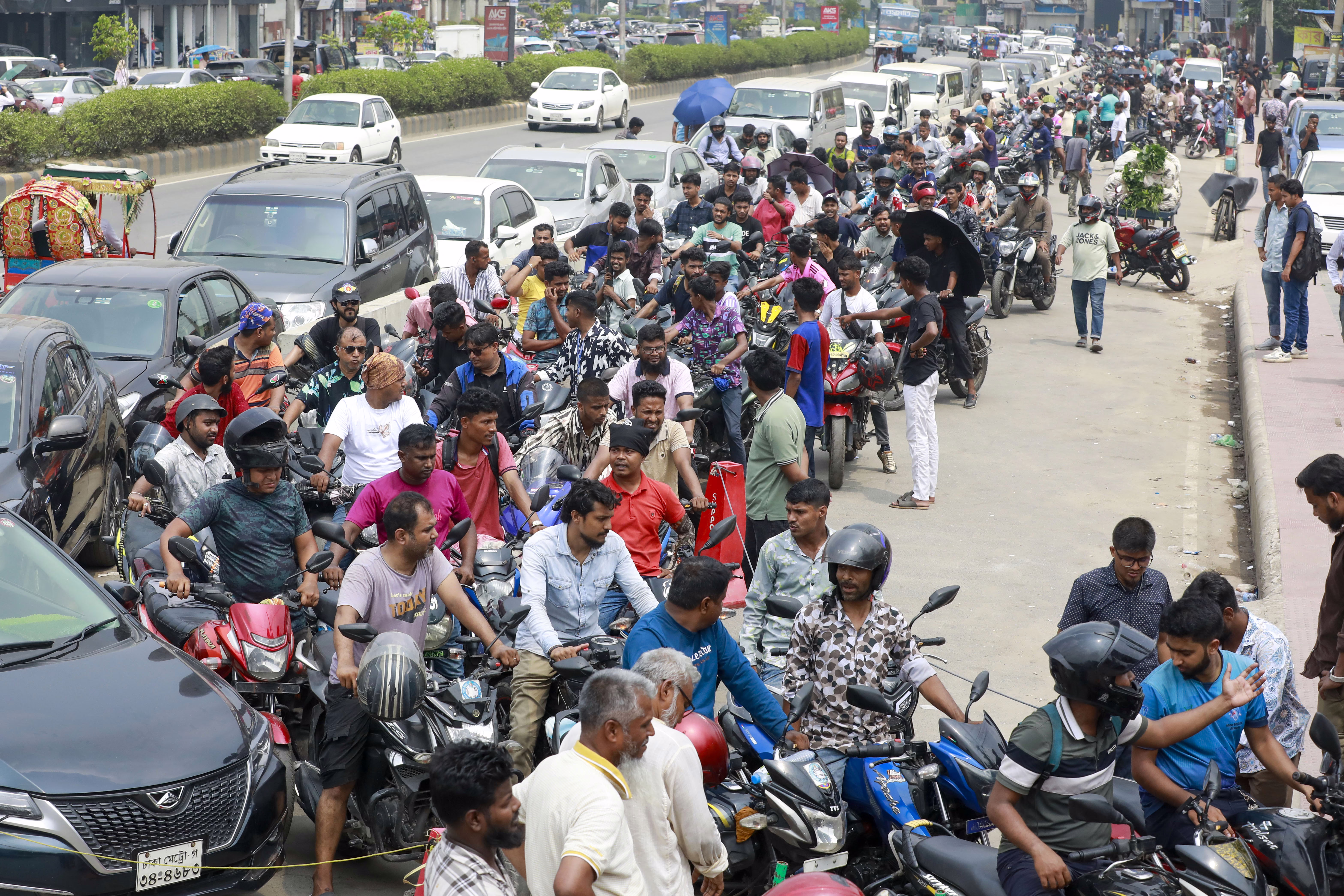 People on scooters wait in a long line to buy fuel.