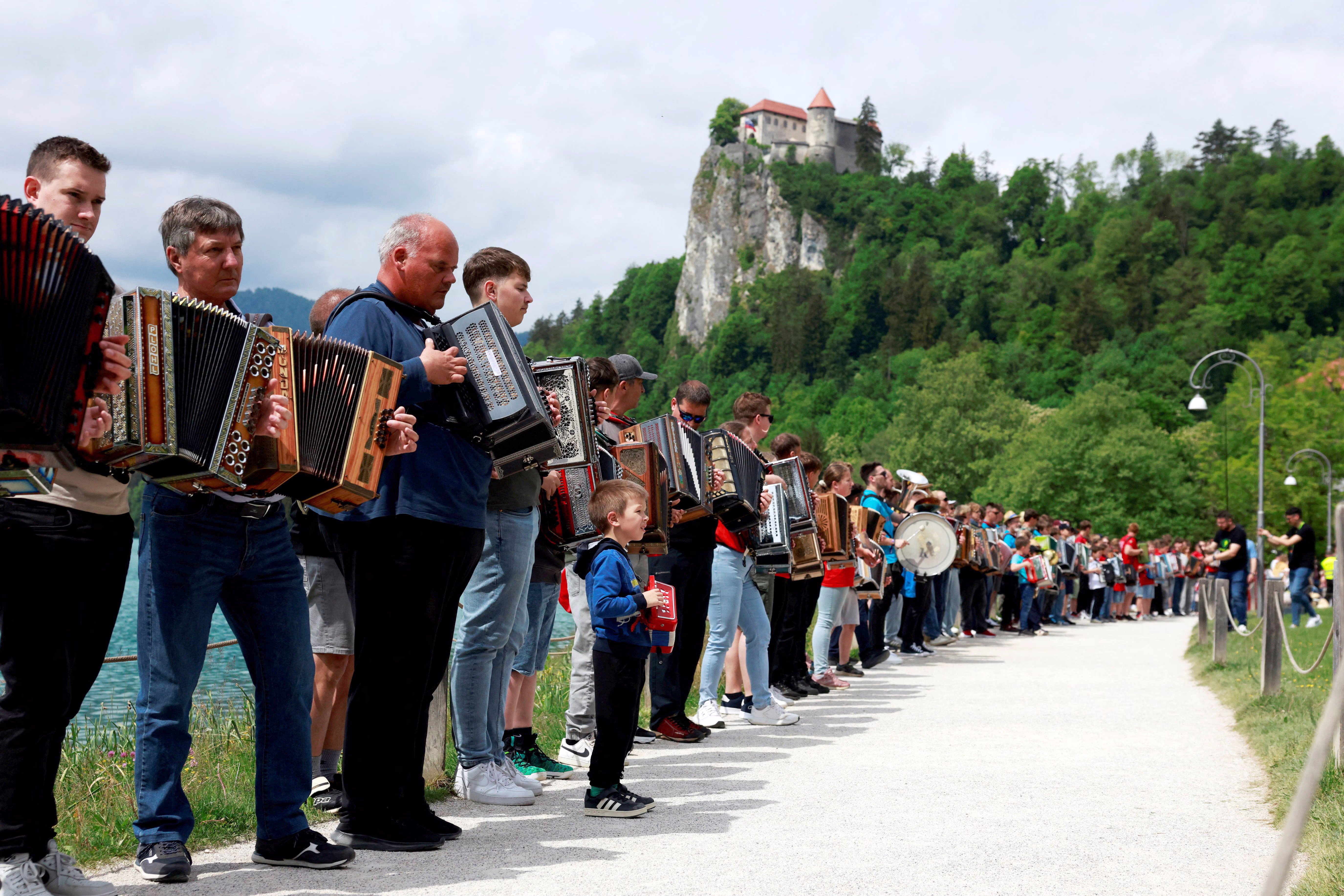 Dozens of accordionists stand side-by-side along a path during a mass performance.