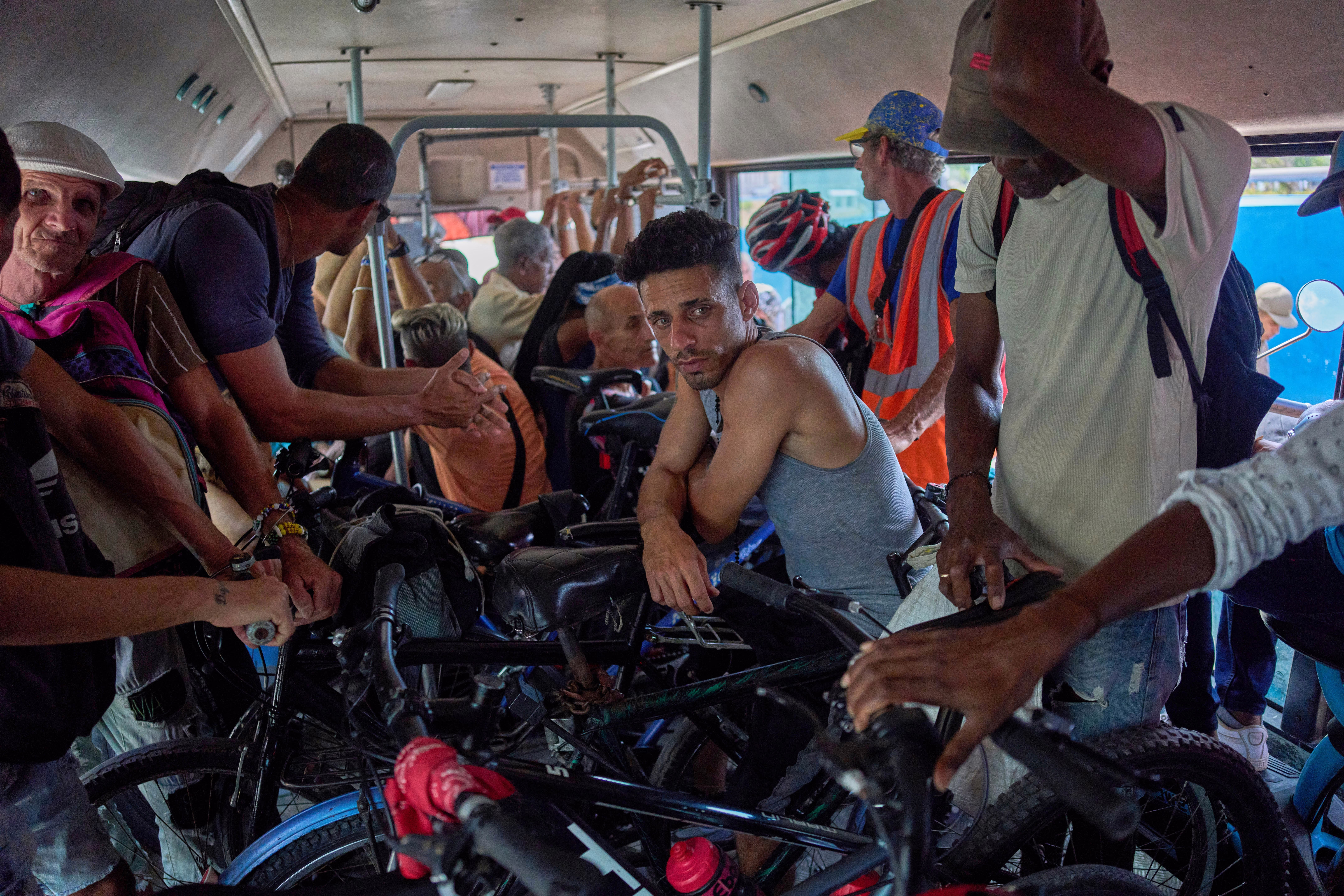 People with bicycles and motorcycles ride inside a public bus.