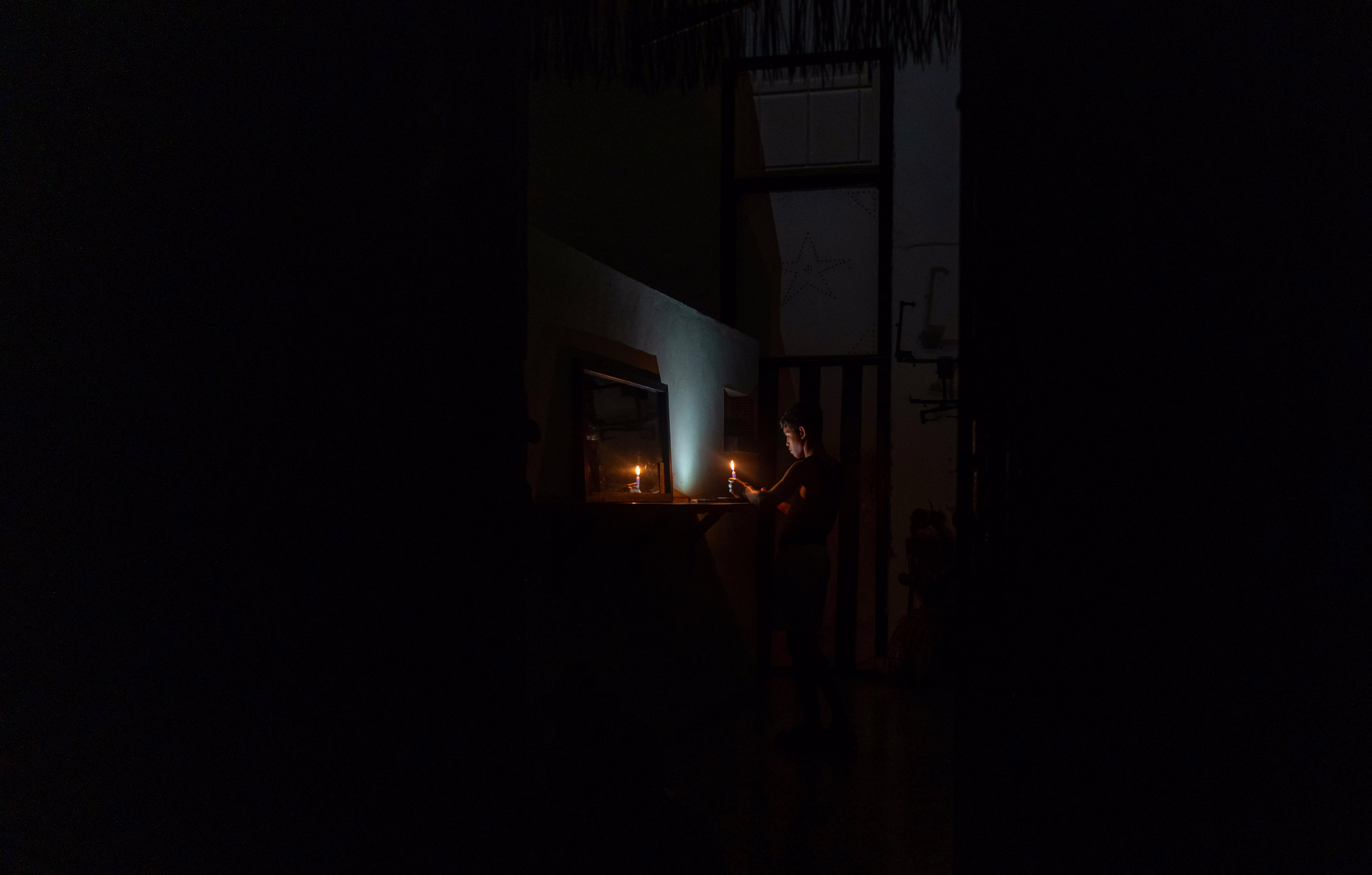 A person lights a candle during a blackout.