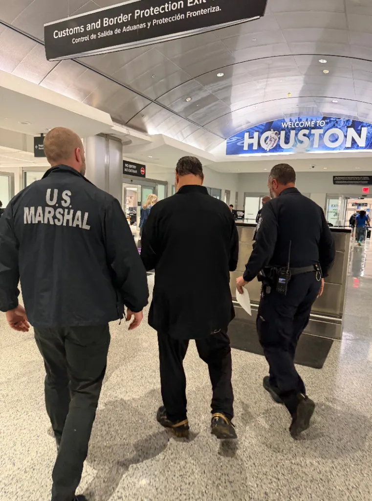 US Marshals escort Werstine through an airport terminal after landing back in the US on May 9, 2026.