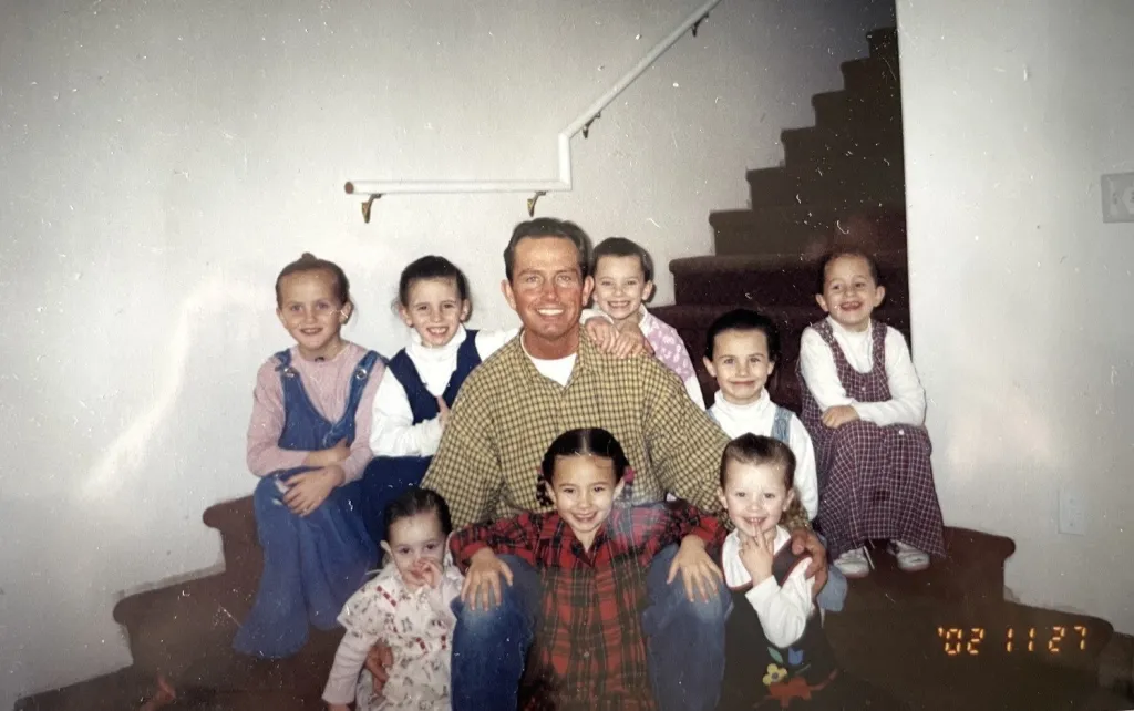 Janet with her father and siblings, sitting on a staircase.