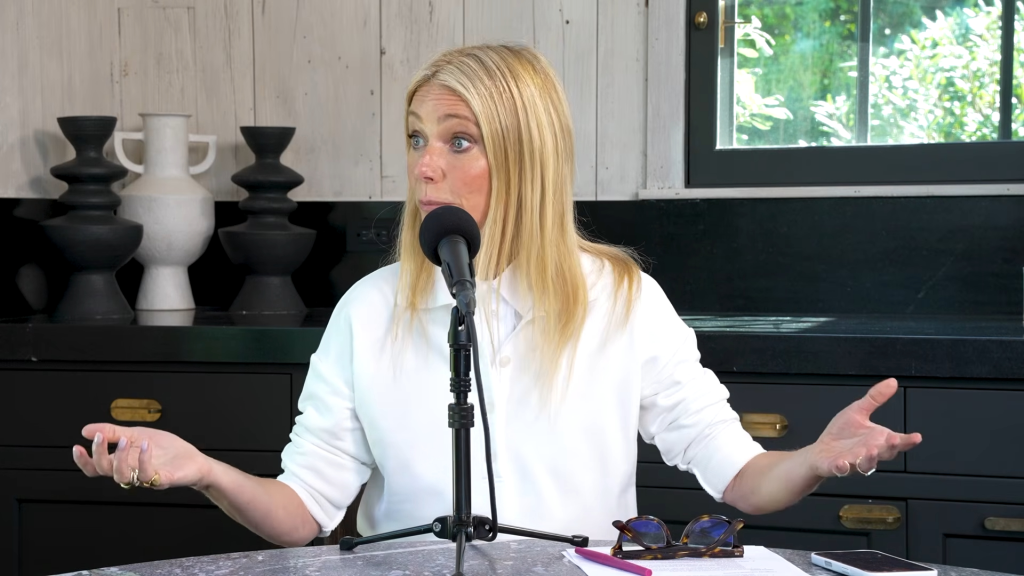 Gwyneth Paltrow speaking into a microphone, gesturing with her hands.