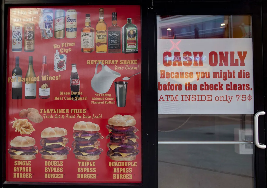 Menu and warnings posted in the window of the Heart Attack Grill in Las Vegas, showing items like 