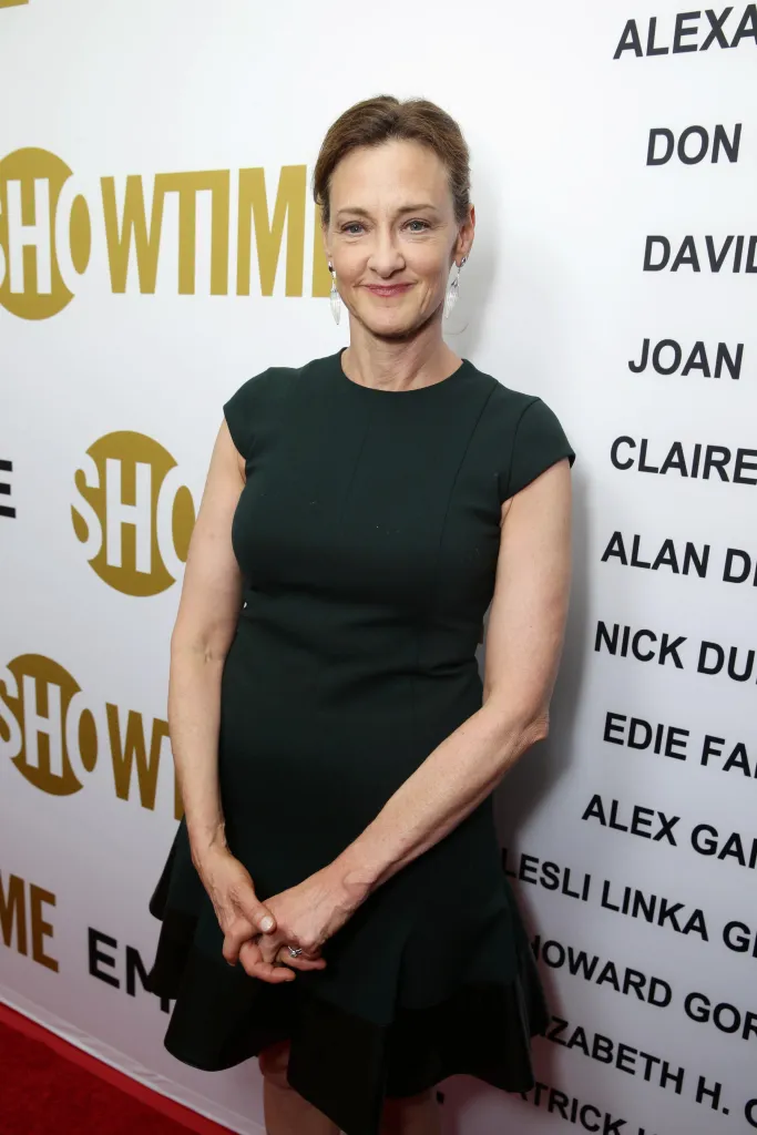 Actress Joan Cusack posing for a photo in a dark green dress with a 