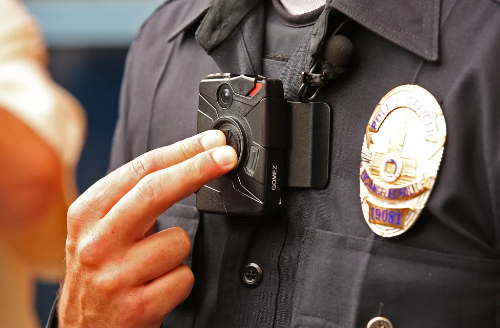 A police officer pressing a button on a body camera attached to his uniform.